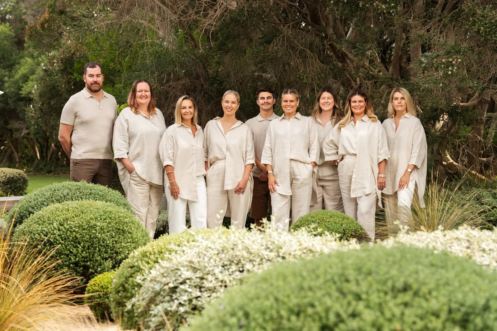 The Future Finance Group team standing together in matching linen outfits in a leafy garden