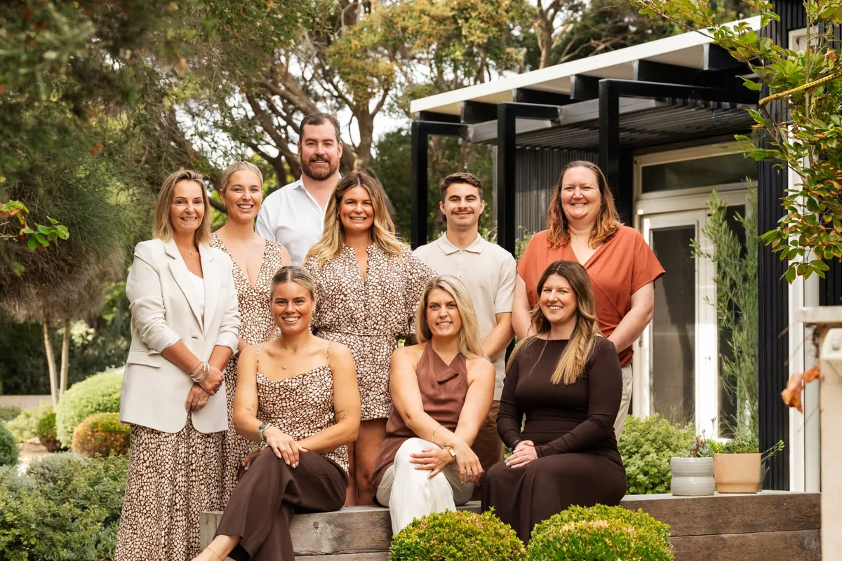 The Future Finance Group team posed outdoors in front of a black building with a pergola